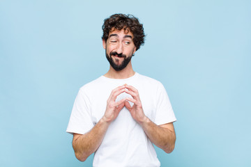 young crazy bearded man feeling proud, mischievous and arrogant while scheming an evil plan or...