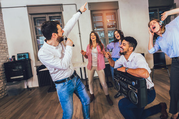 Business people making team training exercise during team building seminar singing karaoke.