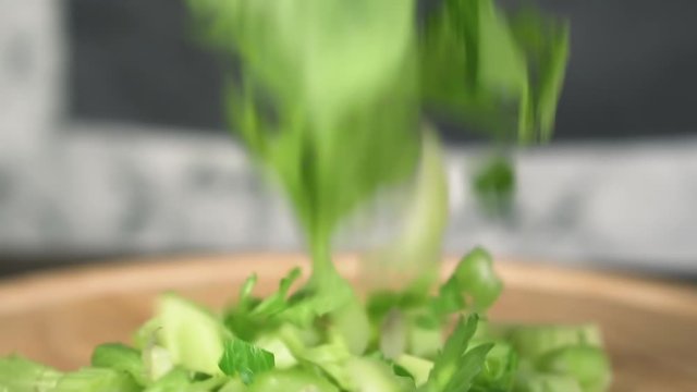 Chopped celery falls on cutting board, slow motion. Concept of healthy food.
