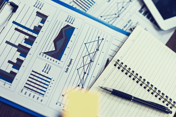 Glasses, book, paper graph and tablet on the table. Object of business concept.
