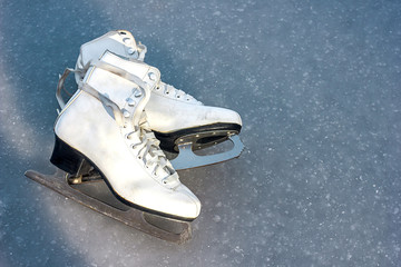 old white figure skates lie on ice, winter outdoor activities, sports health in winter, space for...