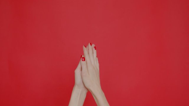 Woman's hands applaud and show a finger gesture fuck you on a red background. Place for text or image.Advertising platform, layout. 