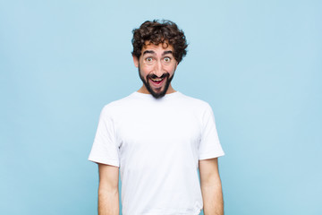 young crazy bearded man looking happy and pleasantly surprised, excited with a fascinated and...