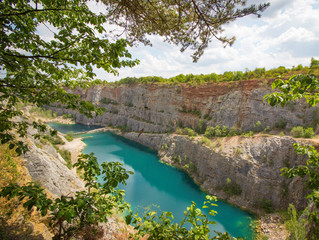 Fototapeta na wymiar A bright blue lake in the middle of quarry