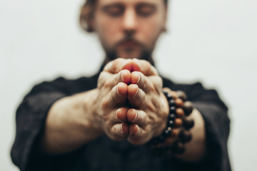 Fingers pointing forward to the camera. Hands folded in prayer. Close-up of palm together. The beads on the wrist. The rosary on hand.