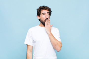 young crazy bearded man yawning lazily early in the morning, waking and looking sleepy, tired and...