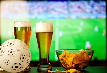 beer glasses and chips in front of tv - watching world cup football at home - soccer supporters