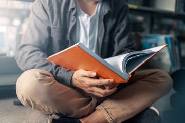 A man hands opening and reading a book at library.