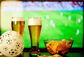 beer glasses and chips in front of tv - watching world cup football at home - soccer supporters