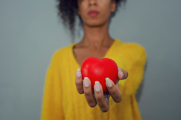 Hand of a black woman holding and offering a heart shape. Love, health concept.