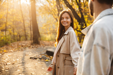 Beautiful smiling young couple walking in the autumn park