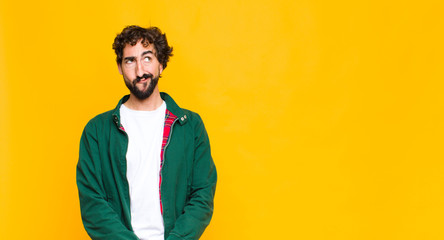 young crazy bearded man looking puzzled and confused, wondering or trying to solve a problem or...