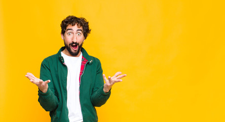 young crazy bearded man open-mouthed and amazed, shocked and astonished with an unbelievable...