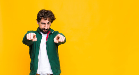 young crazy bearded man pointing forward at camera with both fingers and angry expression, telling...