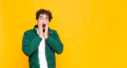 young crazy bearded man feeling shocked and scared, looking terrified with open mouth and hands on...