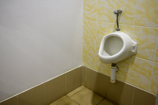 Photo Of A Urinal On A Yellow Tile In A Men's Restroom