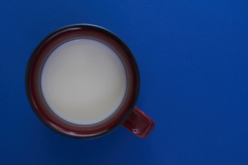 Cup with milk on a blue background.
