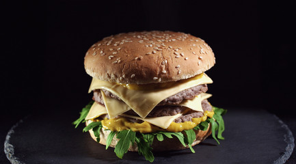 Closeup of king size cheeseburger isolated on black background