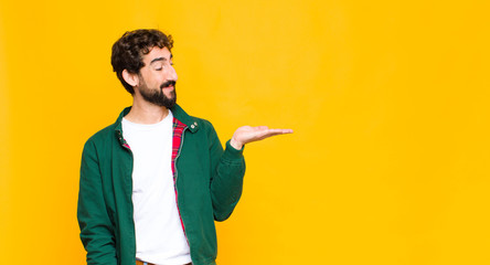 young crazy bearded man feeling happy and smiling casually, looking to an object or concept held on...