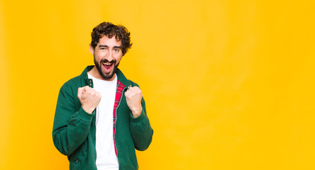 young crazy bearded man shouting triumphantly, laughing and feeling happy and excited while...