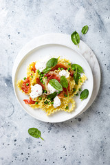 Italian pasta mafalde with green peas, prosciutto, burrata,  and spinach