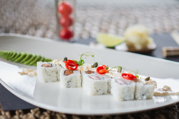 Traditional rolls with fish and rice on a white plate with sauce and wasabi. Japanese food.