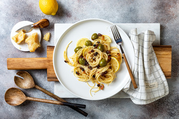 Italian pasta cacio e pepe, spaghetti mixed with grated cheese, green olives, lemon and raisins