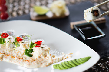 Traditional rolls with fish and rice on a white plate with sauce and wasabi. Japanese food.