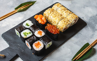 Various kinds of sushi served on a concrete background.