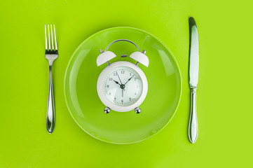 Alarm clock with fork and knife on the table. Time to eat, Breakfast, Lunch Time and Dinner concept