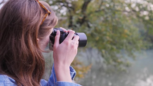 A young female photographer in nature, shoots wildlife in the fall in the woods. Hobby or profession photography