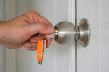 Male hand insert key into keyhole to lock/unlock door.