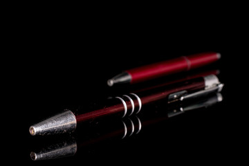 Group of two whole red writing ballpoint pen isolated on black glass