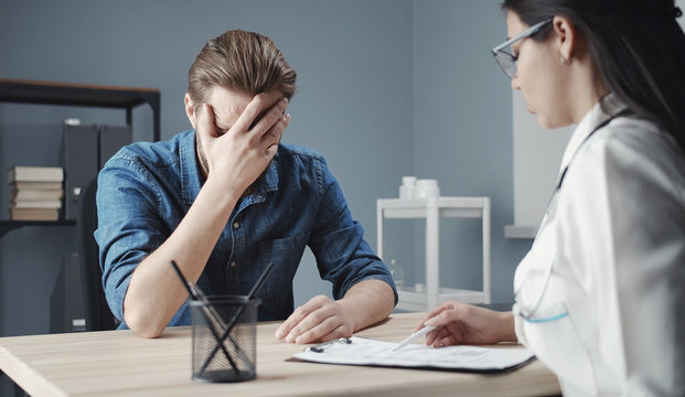 Female Doctor Telling Male Patient Bad News Looking Into Test Results, Man Closing Face With Hand