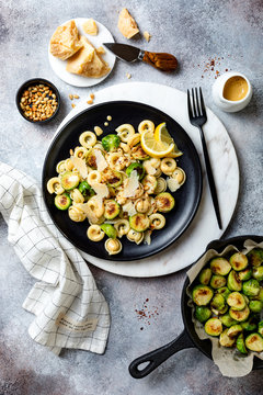 Fresh homemade italian pasta cappelletti with roasted brussels sprouts, pine nuts, parmesan cheese, lemon sauce and red chili flakes