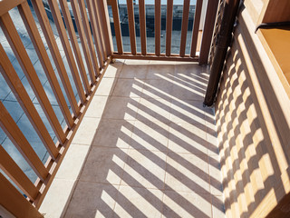 Close-up view of the balcony from the inside under sunlight with pronounced falling shadows from the balcony partitions