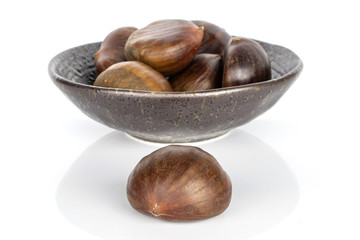 Group of seven whole edible brown chestnut in glazed bowl isolated on white background