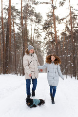 Fototapeta na wymiar Happy lovers a guy and a girl who love each other hug, kiss, laugh, rage and walk in warm jackets in winter against the background of a snowy forest, a friendly family fun walk