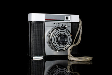 One whole vintage camera one lens isolated on black glass