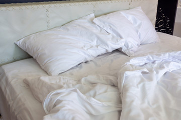 Messy bed. White pillow with blanket on bed unmade. Concept of relaxing after morning.