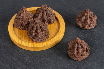 Group of five whole homemade brown coconut cocoa biscuit on bamboo coaster on grey stone