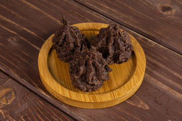 Group of three whole homemade brown coconut cocoa biscuit on bamboo coaster on brown wood