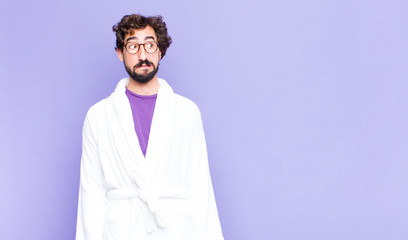 young bearded man wearing bathrobe looking worried, stressed, anxious and scared, panicking and...