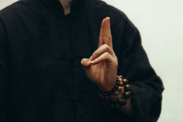 A male yogi sits and shows the mudra of life, and on his hand there is a rosary. Close-up of fingers and the beads on a hand