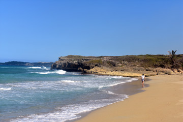 a guy walks on a sandy beach