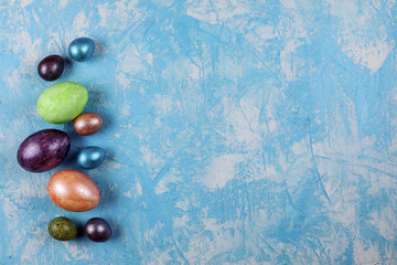 Easter background, colorful eggs on the blue textured background. Copy space.