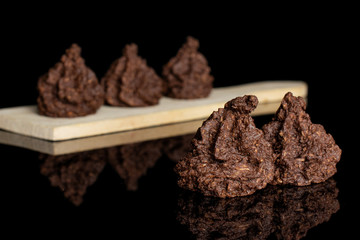 Group of five whole homemade brown coconut cocoa biscuit on small wooden cutting board isolated on black glass