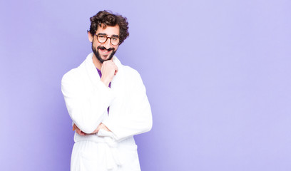 young bearded man wearing bathrobe smiling, enjoying life, feeling happy, friendly, satisfied and...