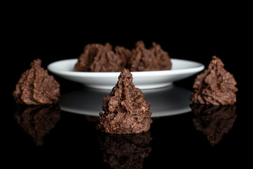Group of seven whole homemade brown coconut cocoa biscuit on white ceramic plate isolated on black glass