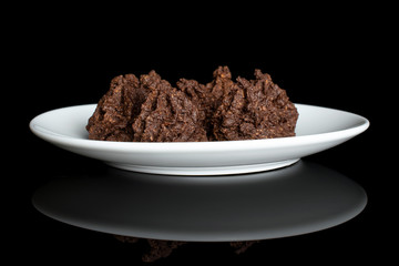 Group of four whole homemade brown coconut cocoa biscuit on white ceramic plate isolated on black glass